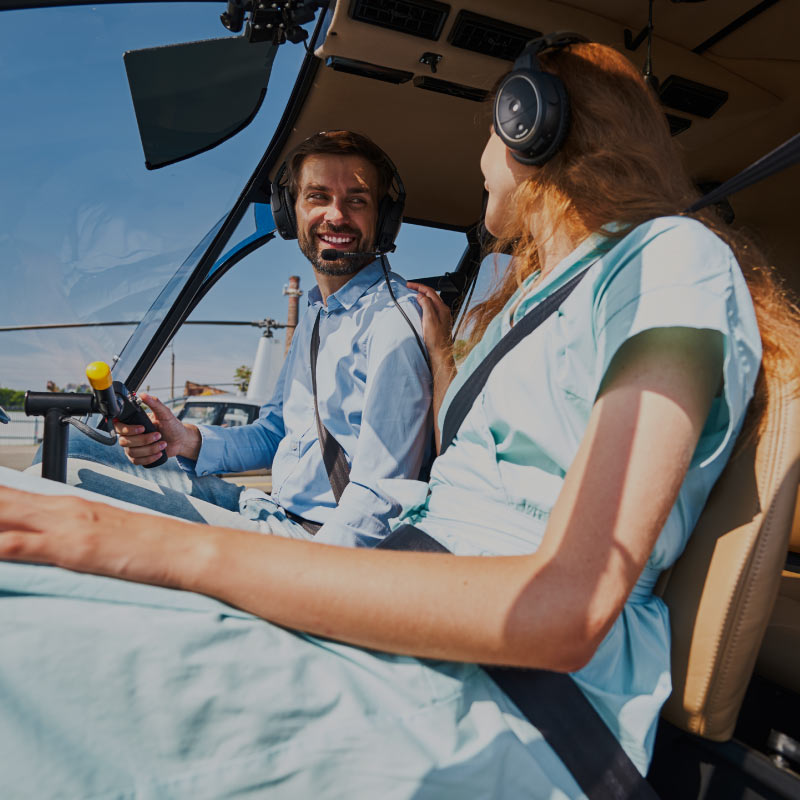 A young couple are sitting in the helicopter, smiling at each other