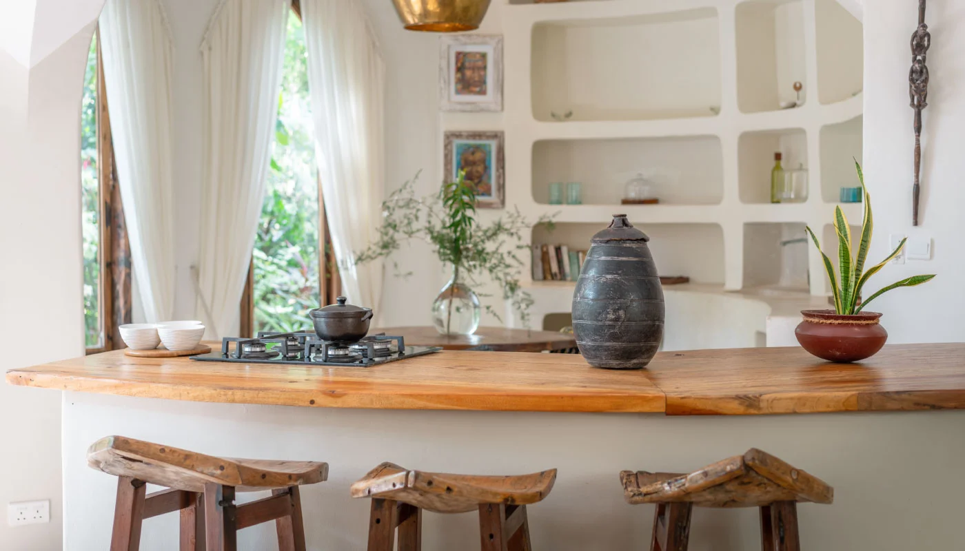 Stylish open kitchen at Mbingu Villa in Xanadu Luxury Villas & Retreat, Zanzibar, featuring a spacious wooden counter, rustic bar stools and a seamless connection to the lounge area.