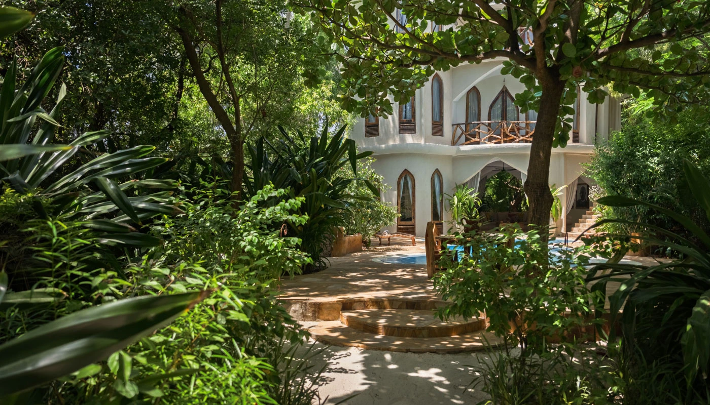 The exclusive Mbingu Villa at Xanadu Luxury Villas & Retreat in Zanzibar, nestled within lush tropical gardens featuring shaded natural stone pathways and a private pool.