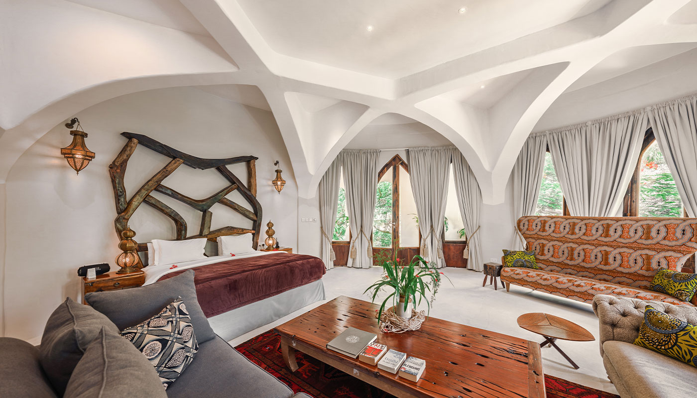 Arched bedroom in Villa Mbingu with a carved wood bed and patterned sofas