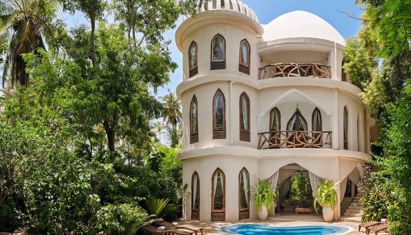 White curved facade of Villa Mbingu beside a small private pool and tropical garden