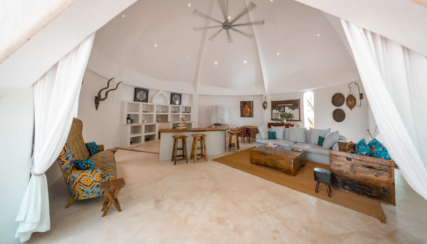 Light-filled living area at Mlima Villa in Xanadu Luxury Villas & Retreat, Zanzibar, featuring a high domed ceiling, comfortable sofas, African design accents and an open kitchen.