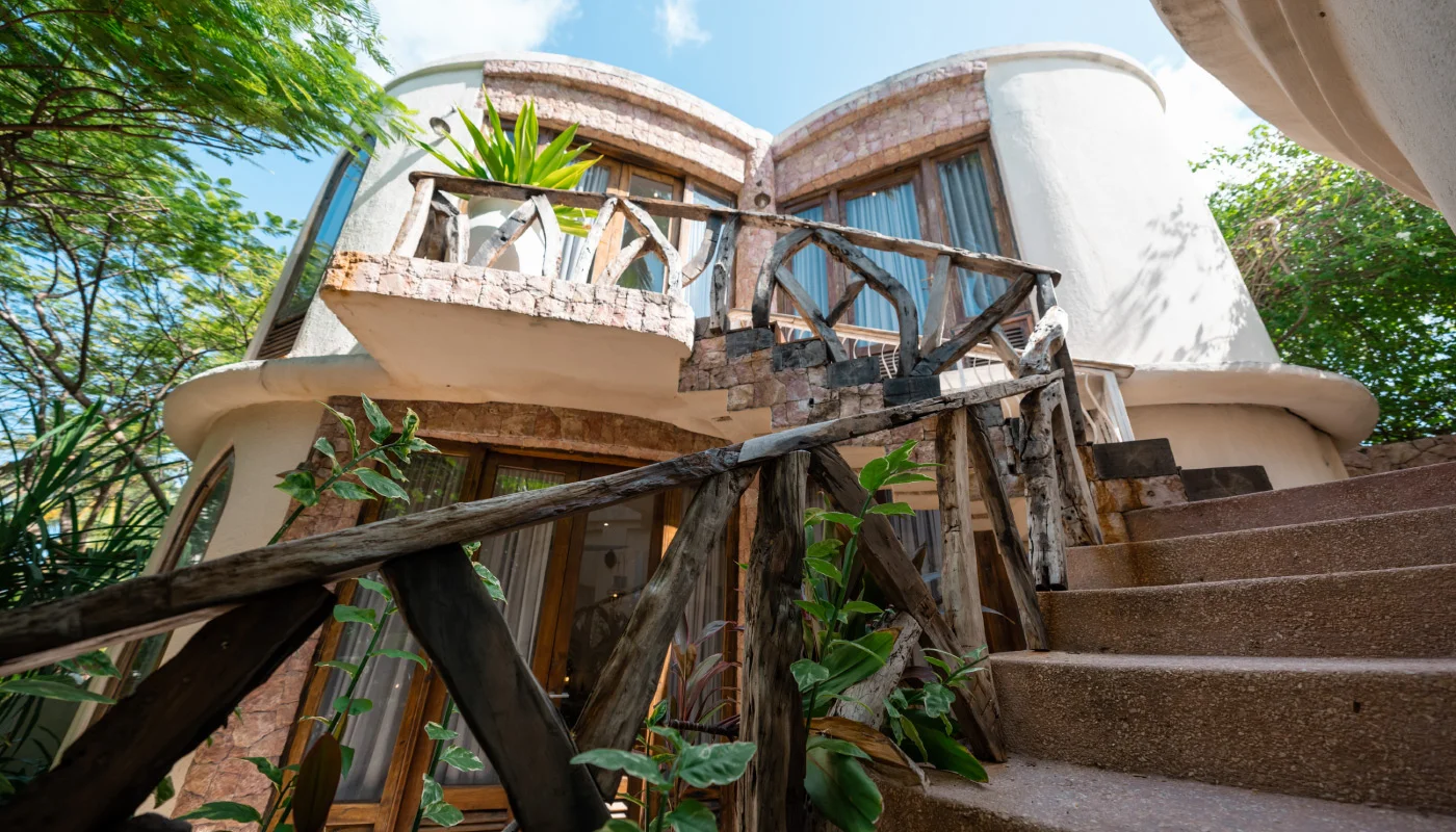 Curved outdoor staircase at Mlima Villa in Xanadu Luxury Villas & Retreat, Zanzibar, featuring rustic wooden railings, natural stone details and elegant balconies surrounded by tropical greenery.