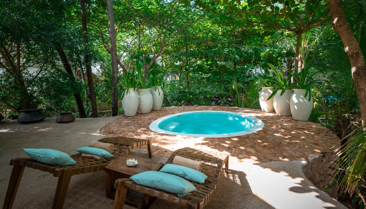 Idyllic private pool at Mlima Villa in Xanadu Luxury Villas & Retreat, Zanzibar, featuring rustic sun loungers, turquoise cushions and lush tropical greenery.