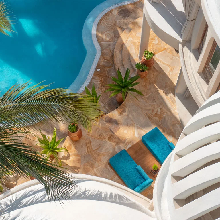 Aerial detail view of Nyota Villa at Xanadu Luxury Villas & Retreat, Zanzibar, overlooking the curved private pool, elegant natural stone surfaces and stylish sun loungers.
