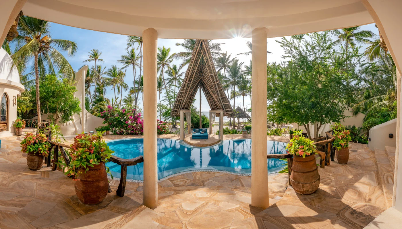 Stunning view from the covered terrace of Nyota Villa at Xanadu Luxury Villas & Retreat, Zanzibar, overlooking the private pool with an exclusive lounge pavilion, tropical palm trees and the Indian Ocean.